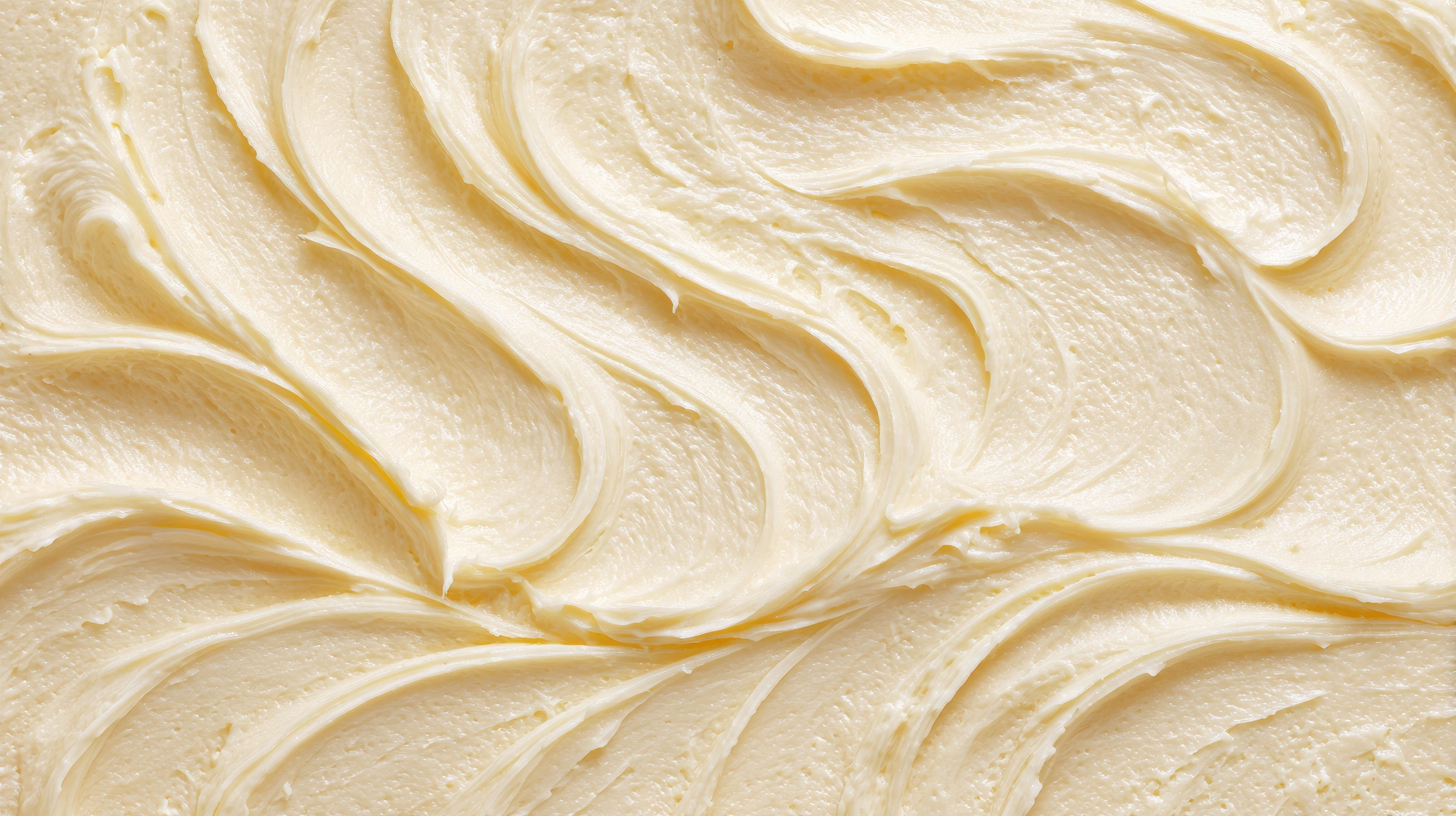 A close-up texture shot of thick, creamy off-white shea butter with soft folds and smooth highlights.